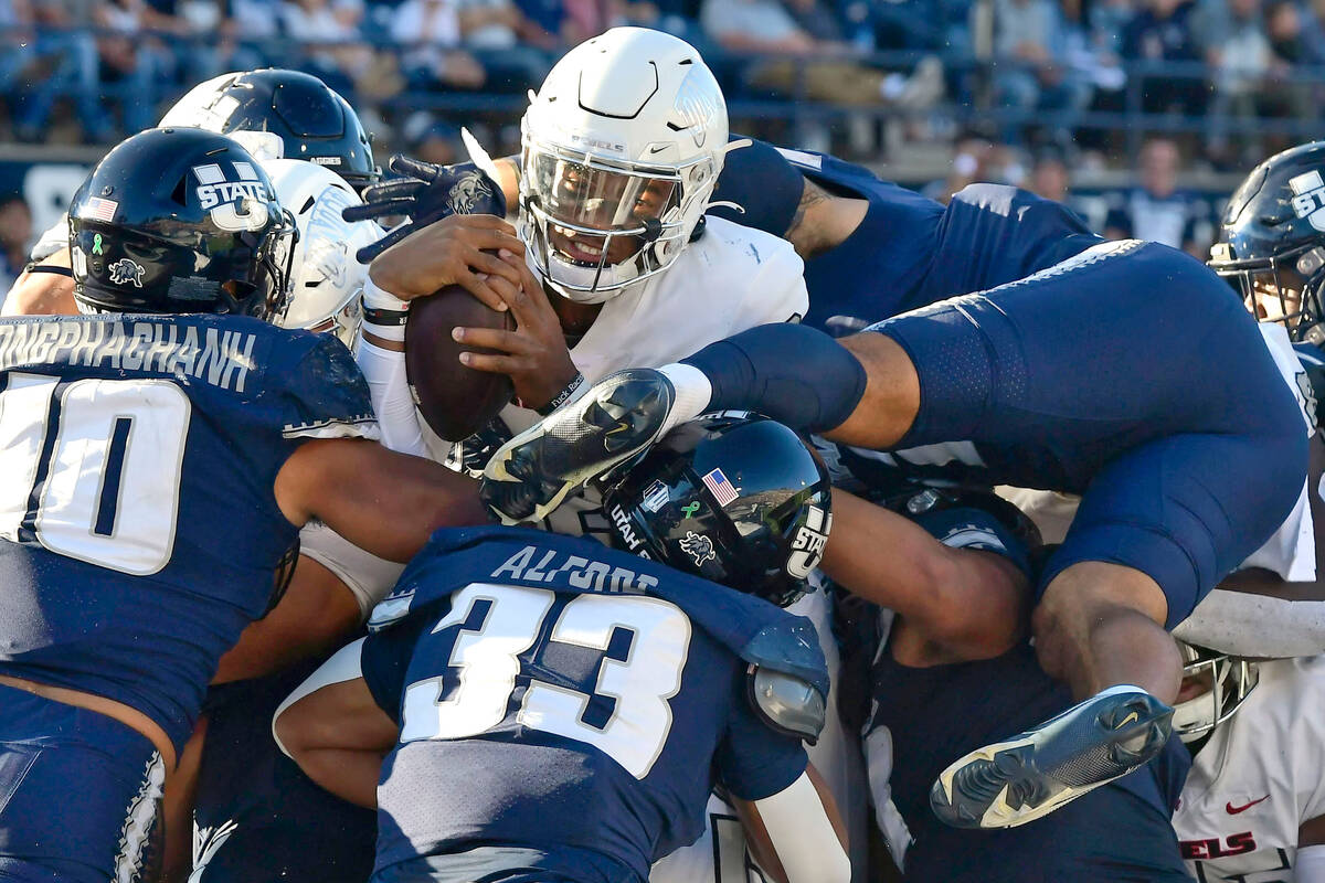 UNLV quarterback Doug Brumfield reaches the ball out to score a touchdown as Utah State linebac ...