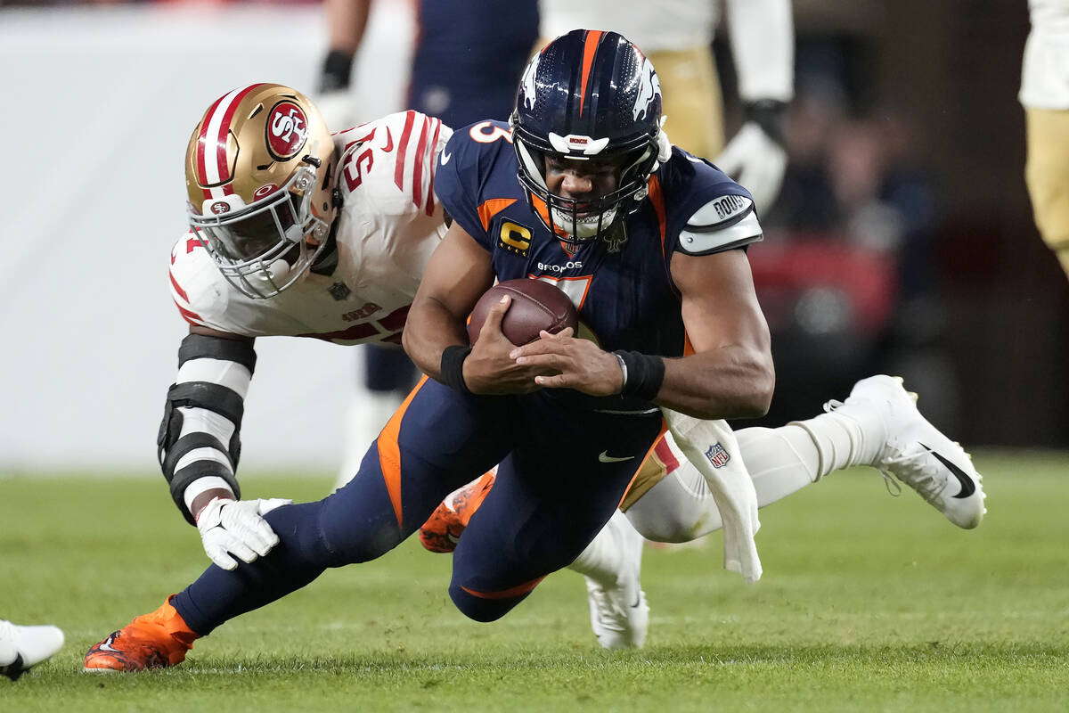 Denver Broncos quarterback Russell Wilson, foreground, is tackled by San Francisco 49ers lineba ...