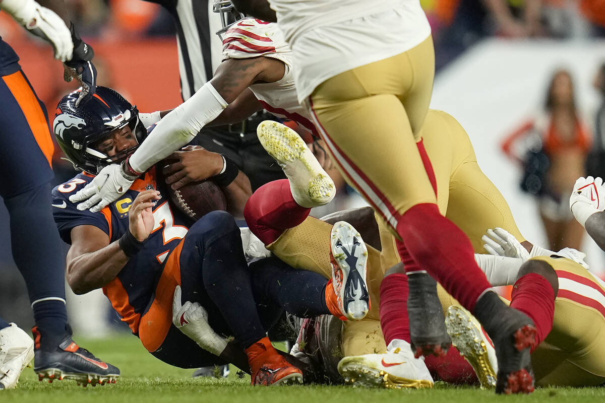 Denver Broncos quarterback Russell Wilson, left, is tackled against the San Francisco 49ers dur ...