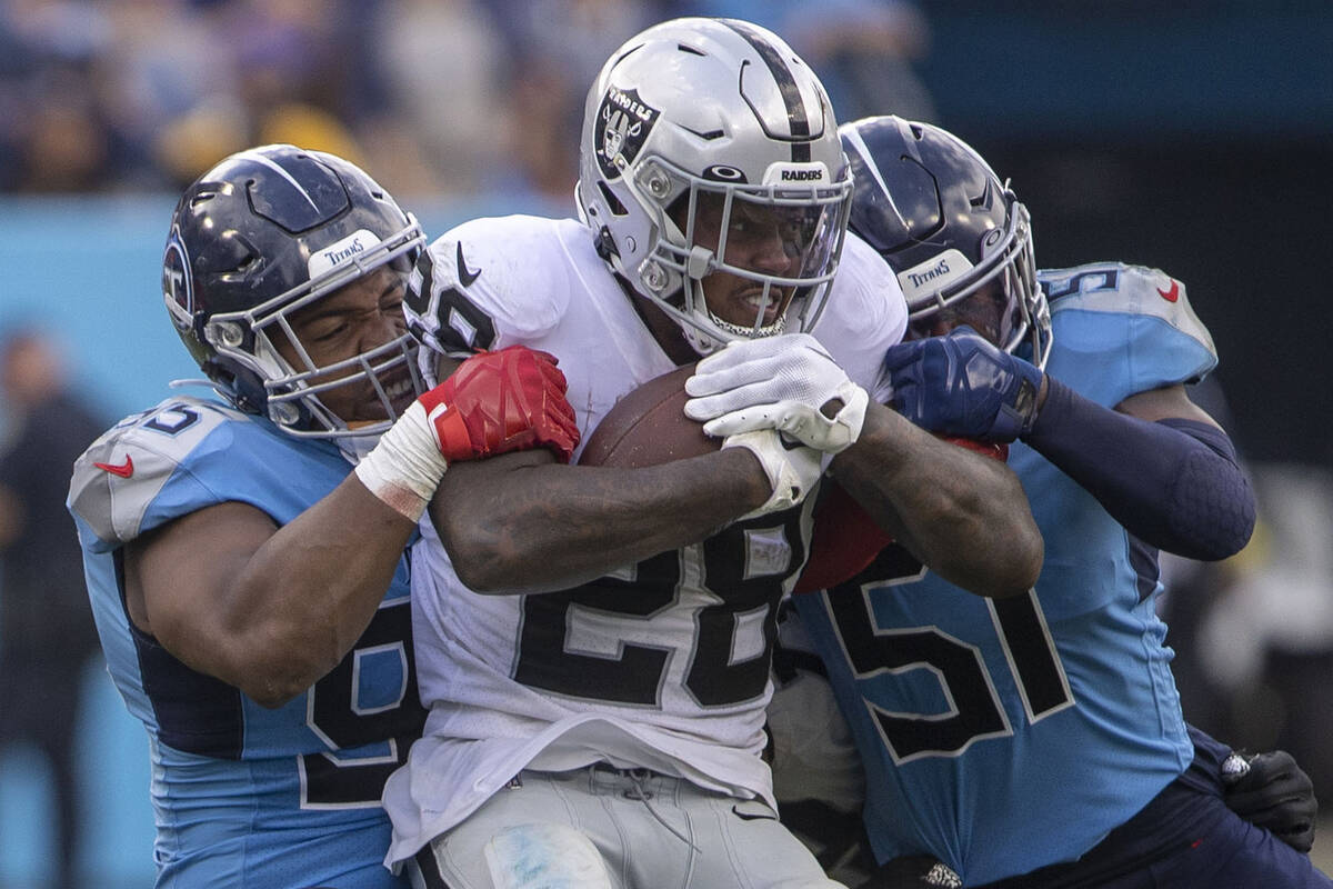 Raiders running back Josh Jacobs (28) is tackled by Tennessee Titans defensive end DeMarcus Wal ...