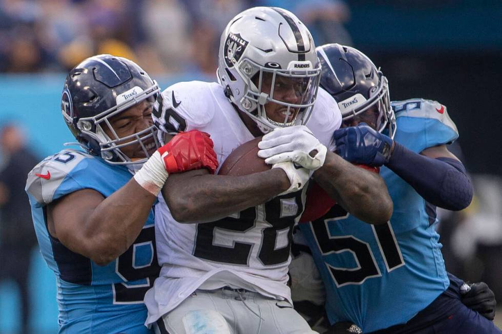 Raiders running back Josh Jacobs (28) is tackled by Tennessee Titans defensive end DeMarcus Wal ...