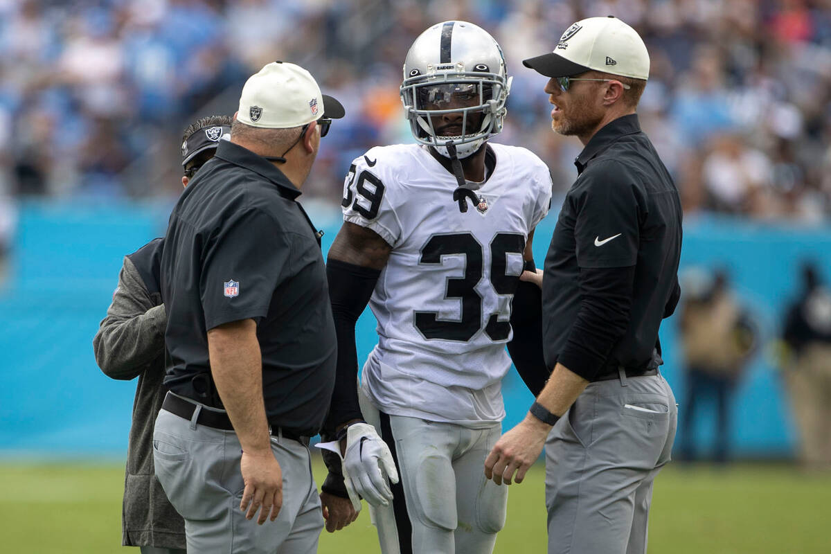 Raiders cornerback Nate Hobbs (39) is helped off the field by trainers during the second half o ...