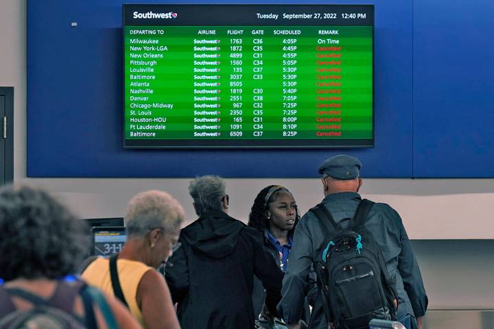 Southwest Airline passengers check into a ticket counter near a sign that shows canceled flight ...