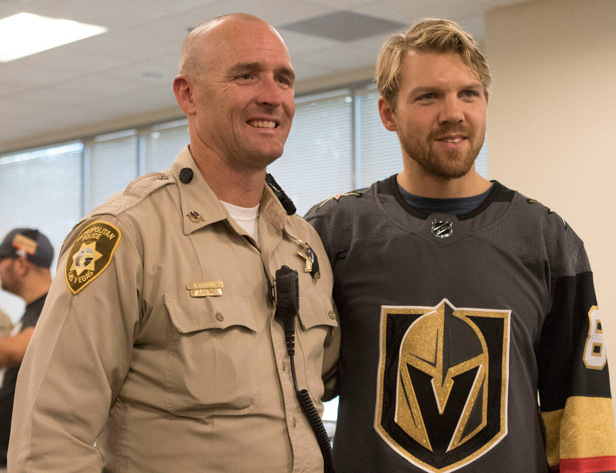 Metro officer Bryan Bertges with Vegas Golden Knights defenseman Griffin Reinhart (8) during a ...