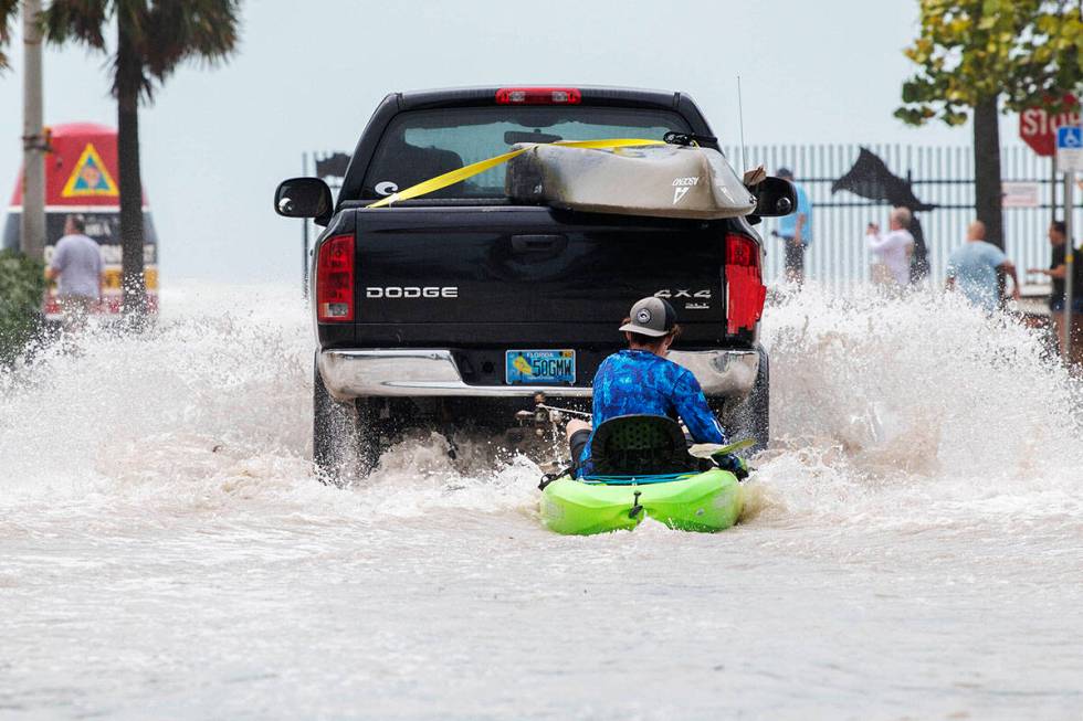 A truck pulls a man on a kayak on a low-lying road after flooding in the aftermath of Hurricane ...