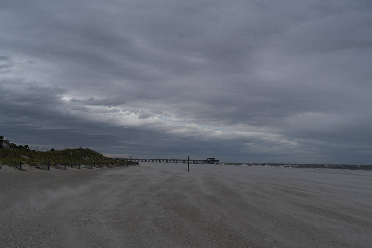 Bands of clouds sweep by a deserted beach as the effects from Hurricane Ian are felt, Thursday, ...