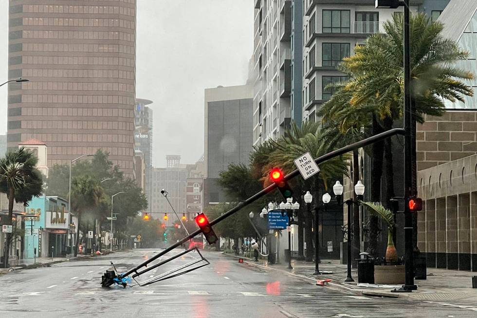 A stoplight pole blown down by Hurricane Ian winds, rests on Orange Avenue in Downtown Orlando, ...