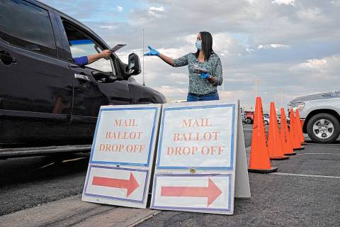 In this Nov. 2, 2020, file photo, a county worker collects mail-in ballots in a drive-thru mail ...