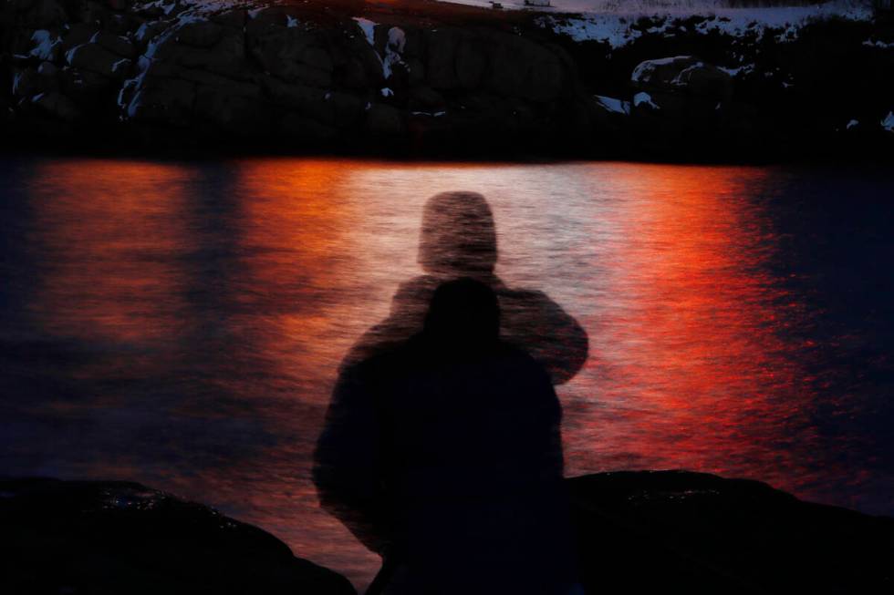 FILE - In this photo made with a long exposure, a man is silhouetted against lights reflected i ...