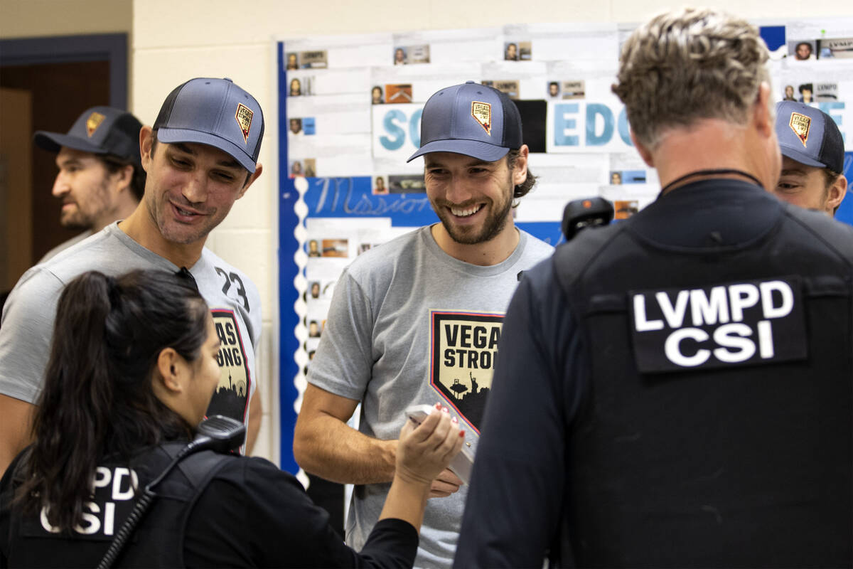 Golden Knights defensemen Alec Martinez and Shea Theodore look a baby photos with members of LV ...