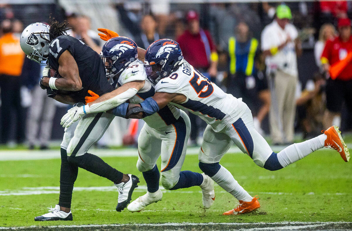 Raiders wide receiver Davante Adams (17) drives for more yards with Denver Broncos linebacker J ...