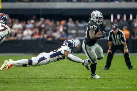 Raiders running back Josh Jacobs (28) shakes off a tackle from Denver Broncos cornerback Ronald ...