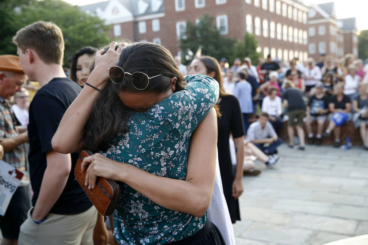 People hug as they gather for a vigil in response to a shooting in the Capital Gazette newsroom ...