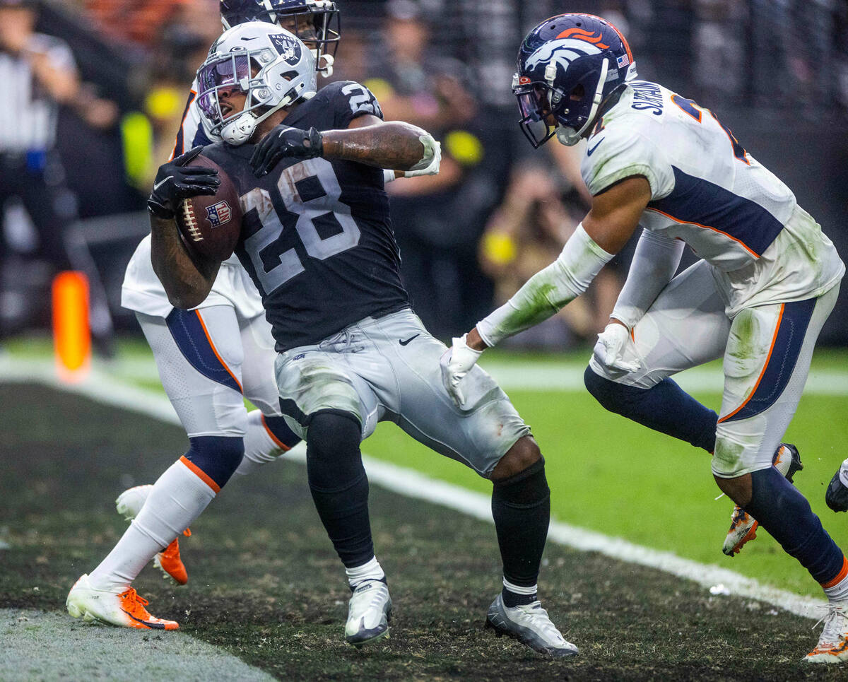 Raiders running back Josh Jacobs (28) spins into the end zone off of a missed tackle by Denver ...