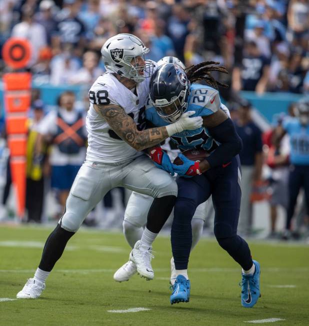 Raiders defensive end Maxx Crosby (98) stops Tennessee Titans running back Derrick Henry (22) d ...