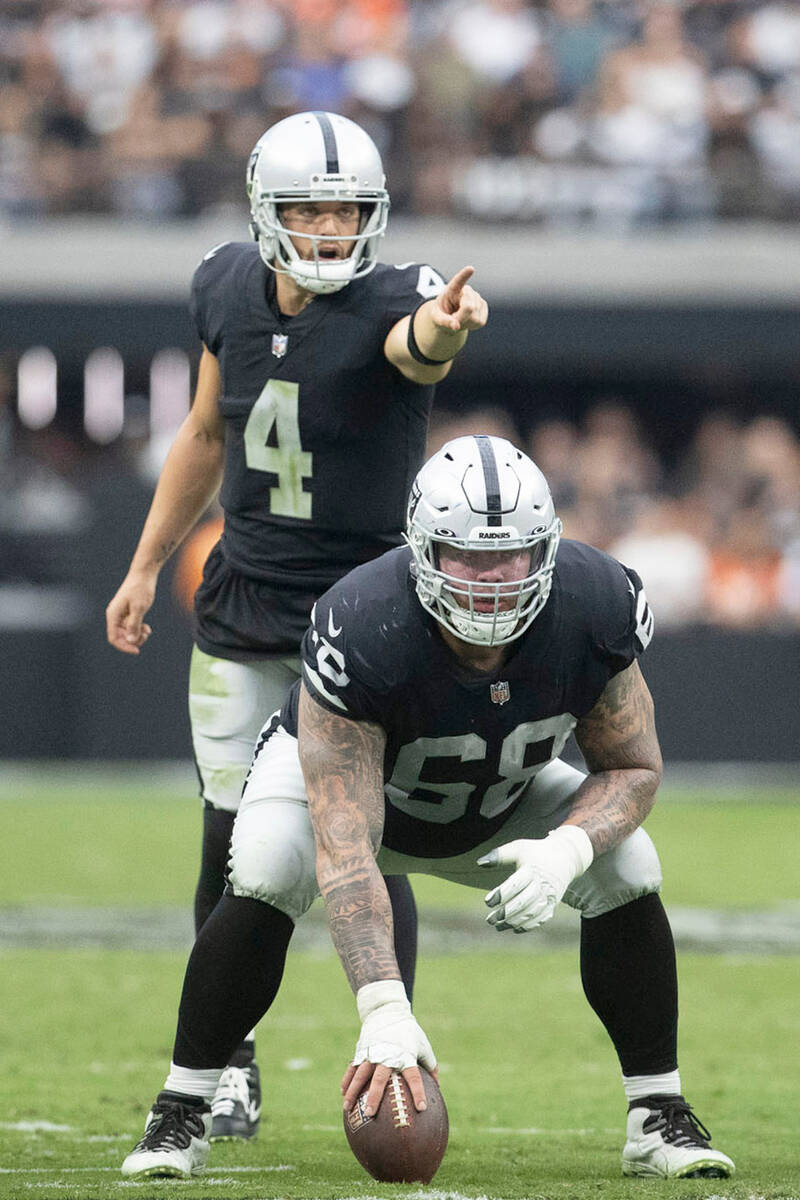 Raiders quarterback Derek Carr (4) calls out instruction at the line of scrimmage as center And ...