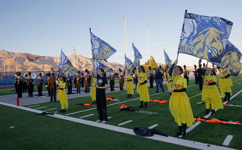 Shadow Ridge High School marching band color guard members perform before a football game again ...