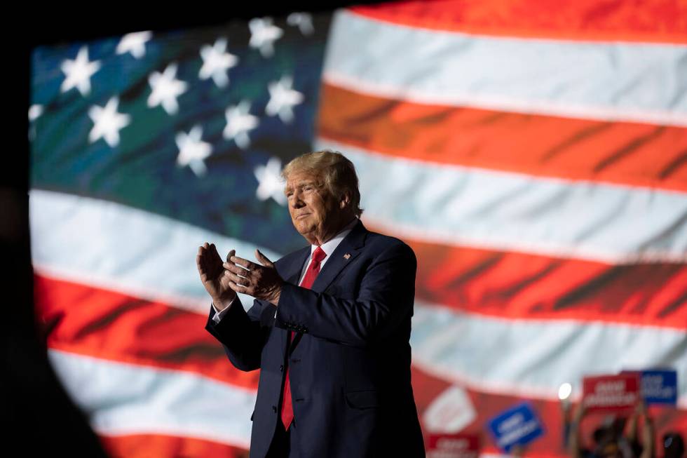 Former President Donald Trump applauds while attending a rally at the Minden Tahoe Airport in M ...