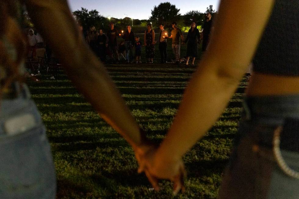 Those who attended a vigil held for Las Vegas Strip stabbing victim Maris DiGiovanni hold hands ...