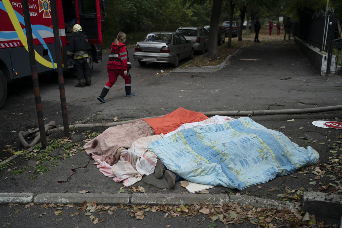 A member of the rescue service walks past three bodies, covered by blankets, following a Russia ...