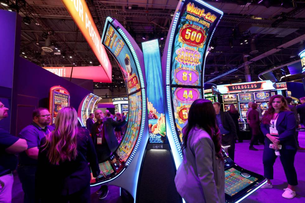Customers check out Whale$ of Cash slot machines in the Aristocrat Gaming booth at the Global G ...