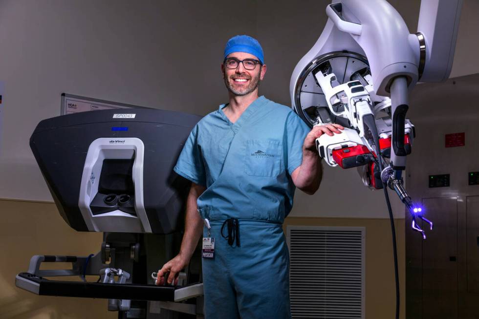 Dr. Garrett Friedman poses for a photo with a da Vinci SP surgical robot in an operating room o ...