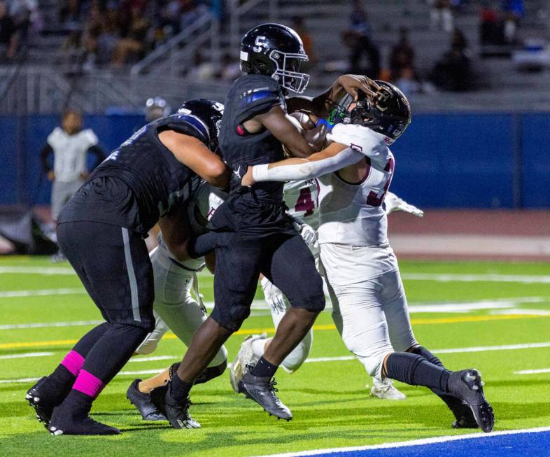 Desert Pines RB Greg Burrell (5) drives through Faith Lutheran's LB Nick Duffy (33) for a score ...