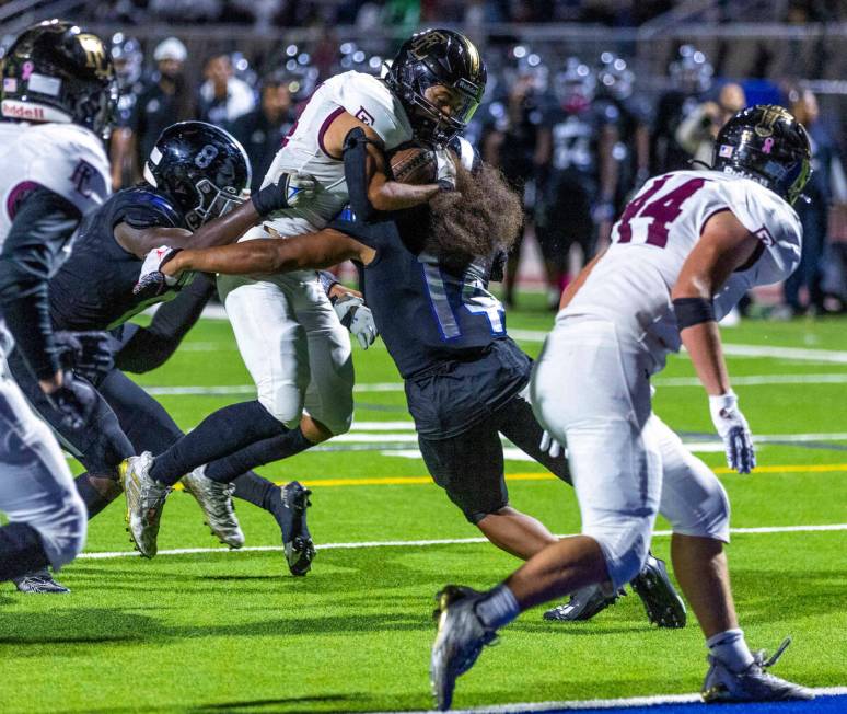 Faith Lutheran's WR Vicentico (Tico) Pringle (4) is met by Desert Pines OLB Isaiah Teo (14) bef ...