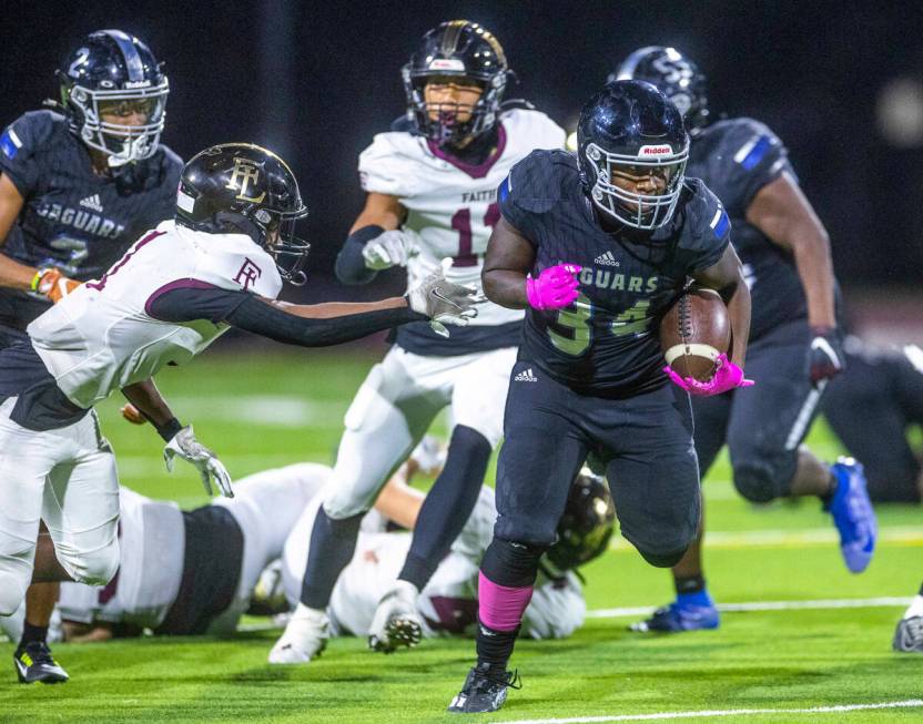 Desert Pines RB Malik Jones (34) evades a tackle attempt by Faith Lutheran's CB Nehemiah Brooks ...