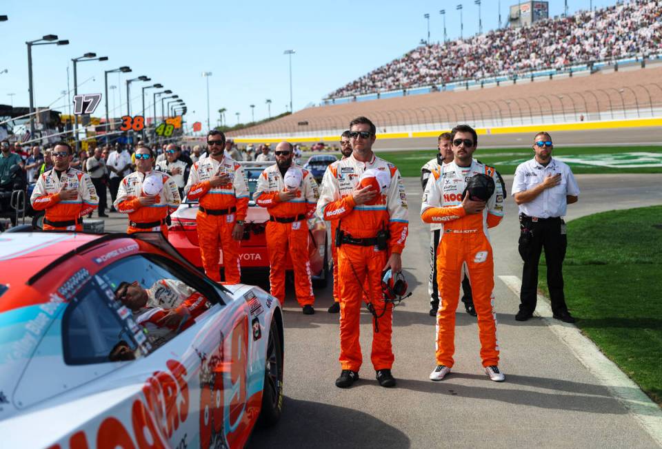 NASCAR Cup Series driver Chase Elliott, right, stands for the national anthem with his pit crew ...