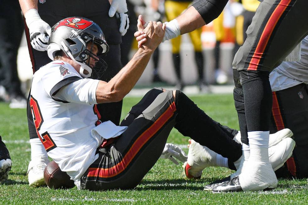 Tampa Bay Buccaneers quarterback Tom Brady (12) is helped up after a play during the first half ...