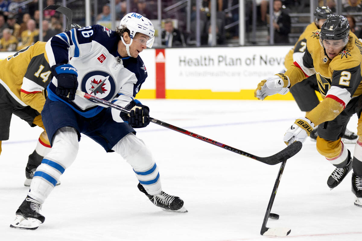 Golden Knights defenseman Zach Whitecloud (2) battles for the puck with Jets center Morgan Barr ...