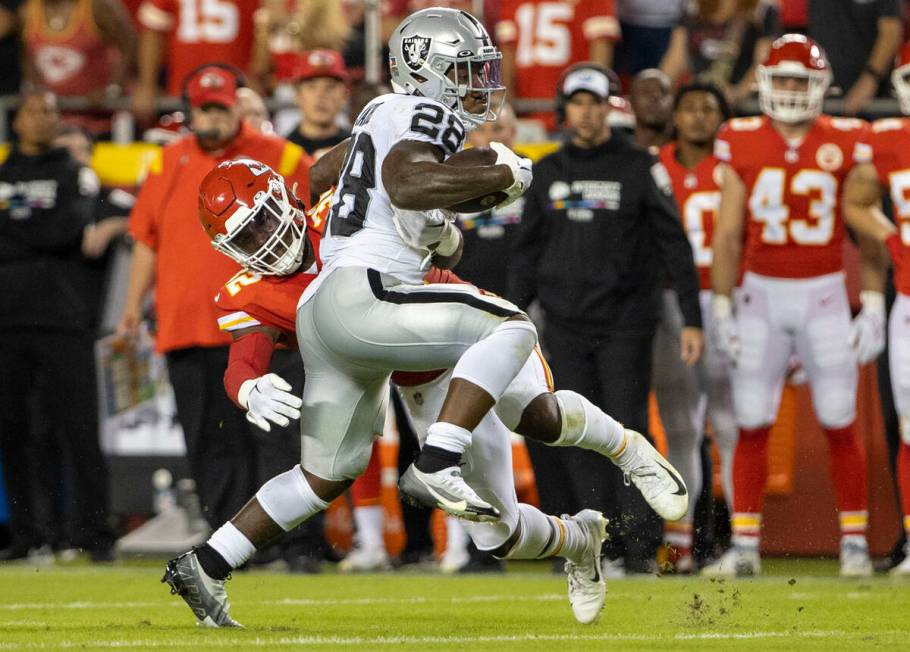 Raiders running back Josh Jacobs (28) runs past Kansas City Chiefs linebacker Nick Bolton (32) ...