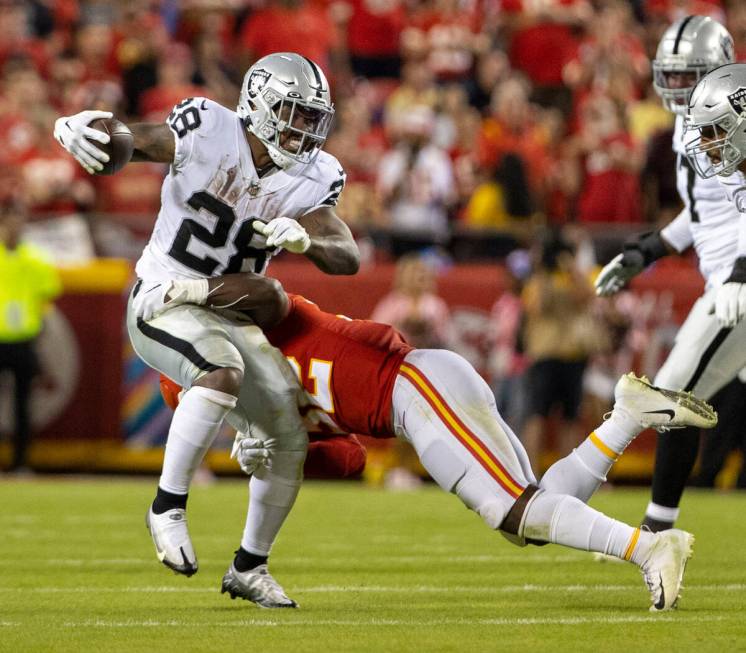 Raiders running back Josh Jacobs (28) looks for room to run as Kansas City Chiefs linebacker Ni ...