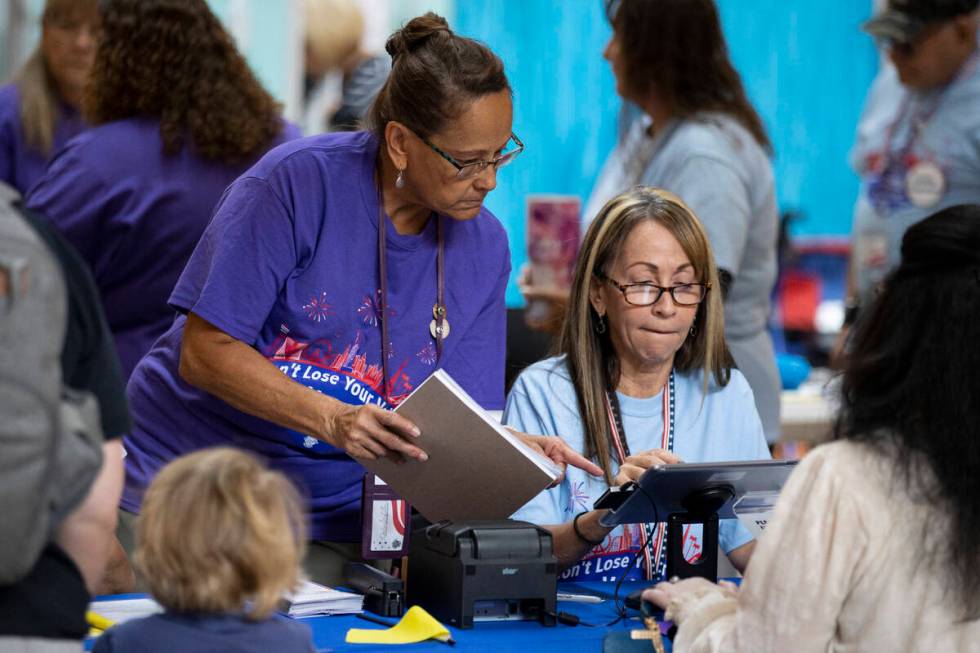 Poll workers Brigitte Benadi-Reaney, left, and Nadine Singleton, assist a voter at the polling ...