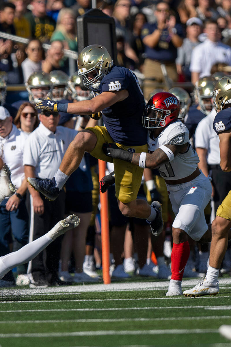 Notre Dame tight end Michael Mayer (87) jumps while being tackled by UNLV linebacker Austin Aji ...