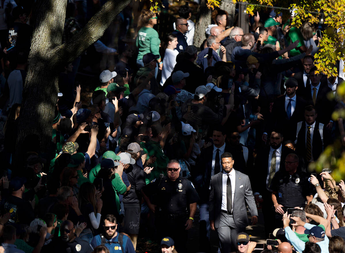 Notre Dame head coach Marcus Freeman, lower right, walks through the crowd during the team walk ...
