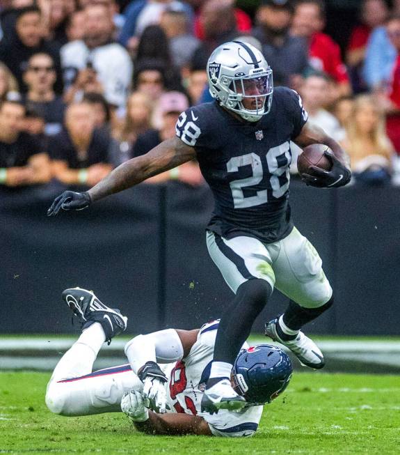 Raiders running back Josh Jacobs (28) evades tackle by Houston Texans defensive end Rasheem Gre ...