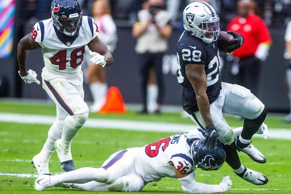 Raiders running back Josh Jacobs (28) is tackled from behind by Houston Texans safety Jonathan ...