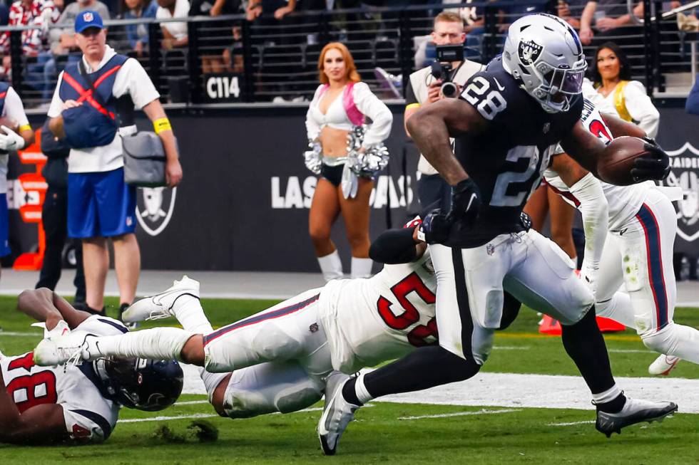 Raiders running back Josh Jacobs (28) gets past Houston Texans defensive tackle Thomas Booker I ...