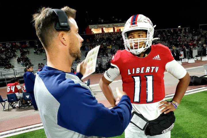 Liberty offensive coordinator Mark Bly talks with quarterback Tyrese Smith during the Patriots' ...