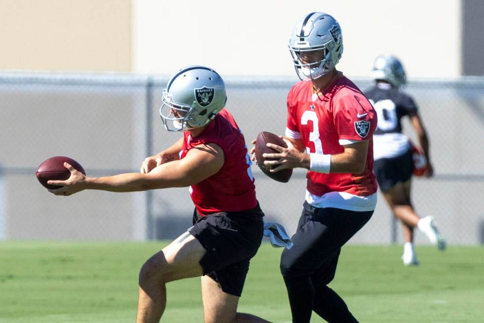 Raiders quarterbacks Derek Carr (4) and Jarrett Stidham (3) work on hand-offs during practice a ...