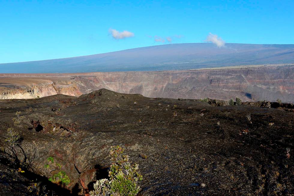 FILE - Hawaii's Mauna Loa volcano, background, towers over the summit crater of Kilauea volcano ...