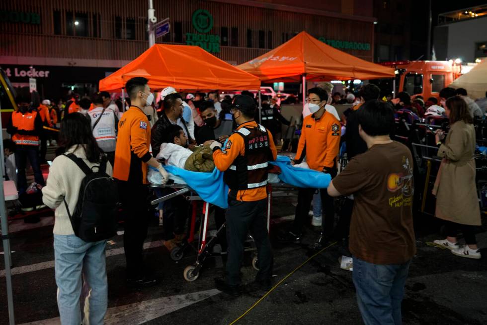 Rescue workers carry injuried people at the street near the scene in Seoul, South Korea, early ...