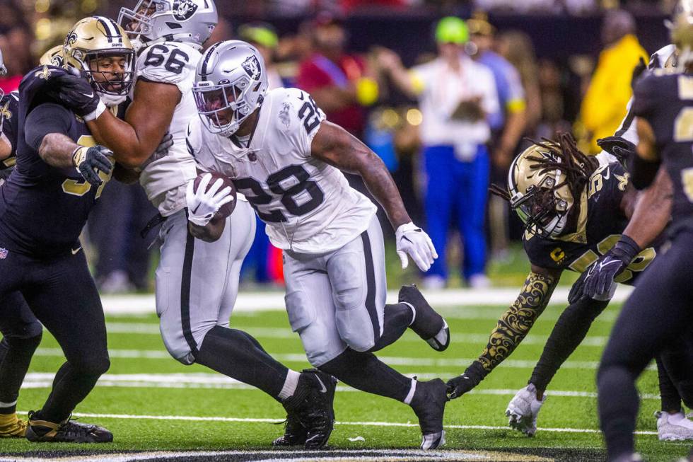 Raiders running back Josh Jacobs (28) breaks through the defensive line as New Orleans Saints l ...