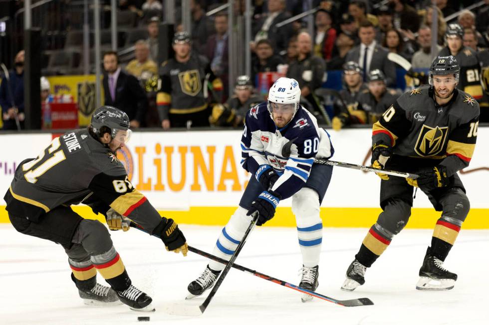 Winnipeg Jets left wing Pierre-Luc Dubois (80) passes the puck between Vegas Golden Knights rig ...