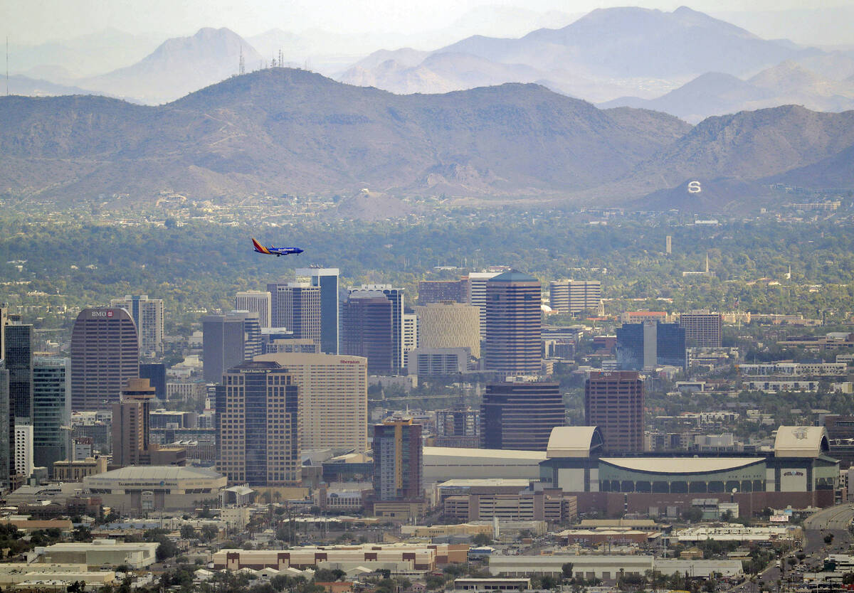 In this Tuesday, July 24, 2018 photo, a jet comes in for approach over downtown Phoenix. (AP Ph ...