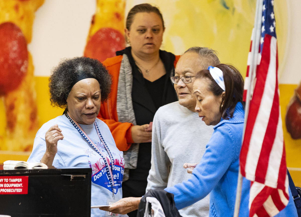 Alicia John, an election worker, watches as voters, who declined to give their names, place the ...