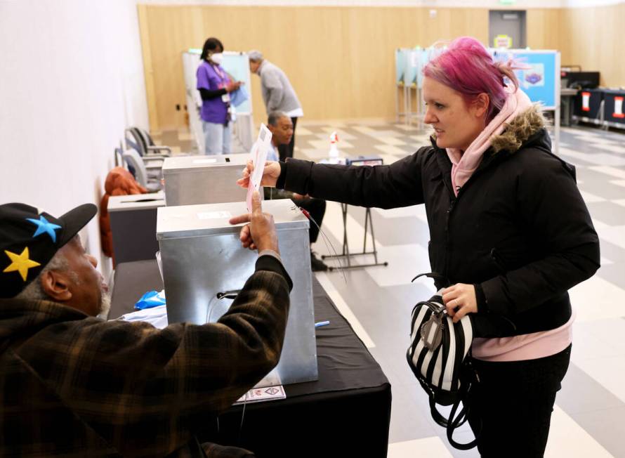 Valeria Piotto of Las Vegas drops her ballot as poll worker William Redic looks on at East Las ...