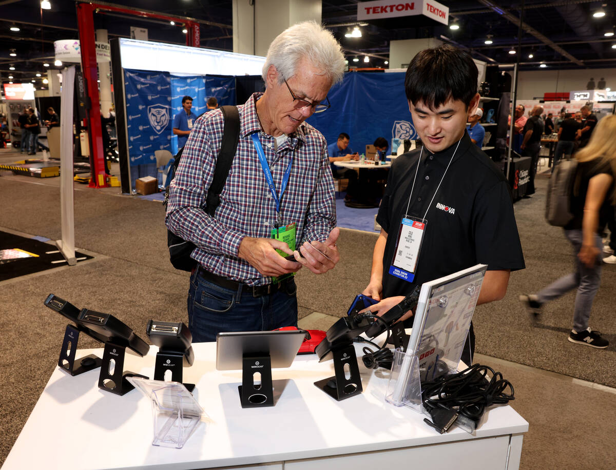 Cole Kong of Innova Electronics in Irvine, Calif. shows a diagnostic tool to Richard Schmidt of ...